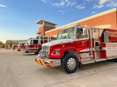A photo of several firetrucks parked outside of the Steinbach Fire Hall on a sunny day