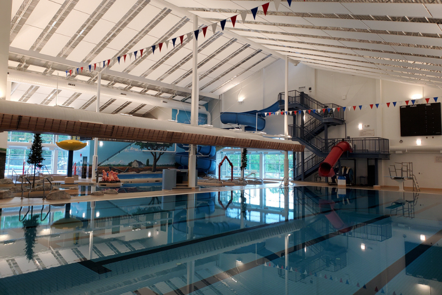 Interior of a brightly lit Steinbach Aquatic Centre featuring its new renovations and the lap pool, leisure pool, slides, and water features.