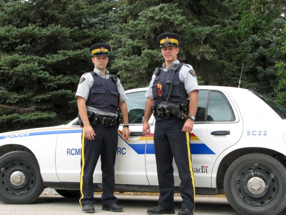 Two RCMP officers standing by an RCMP vehicle.