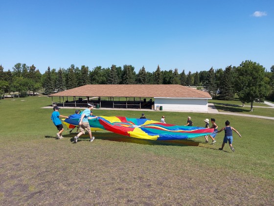Campers playing with rainbow parachute at AD Penner Park.