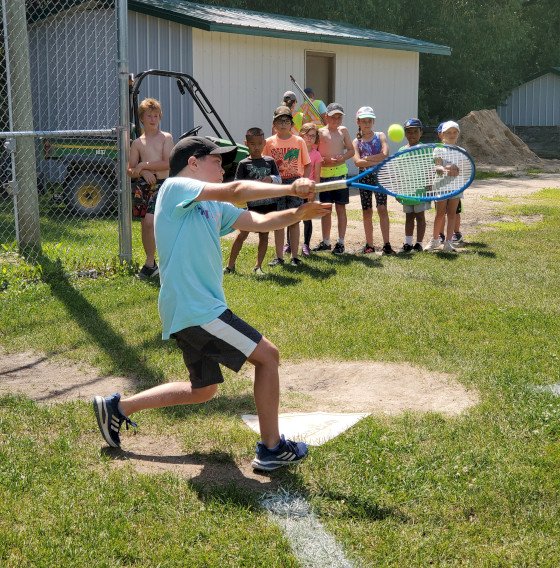 Camper swinging a tennis racket.